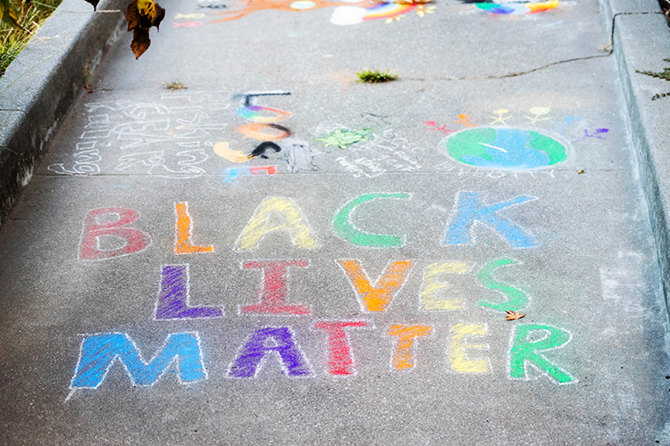 A black lives matter chalk drawing made with red, orange, purple, yellow, blue and green chalk