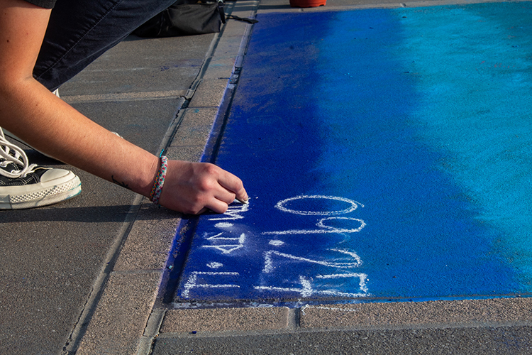 A hand signing a chalk mural