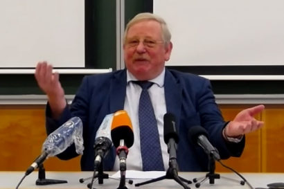 Genzel sitting in front of microphones at a press conference in Germany