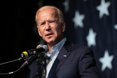 Joe Biden, standing before the stars of an American flag, gives a speech