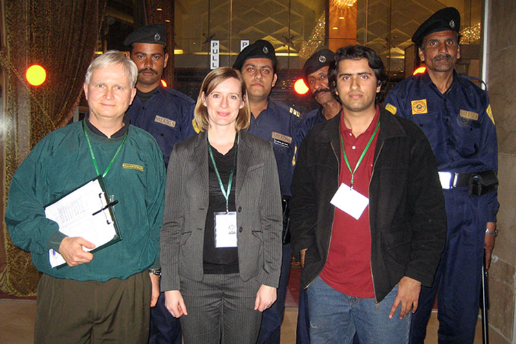 Susan Hyde (front row, center) stands with a colleague, an interpreter and a security detail during travel to Islamabad, Pakistan, in 2008 as part of a Democracy International election observation mission.