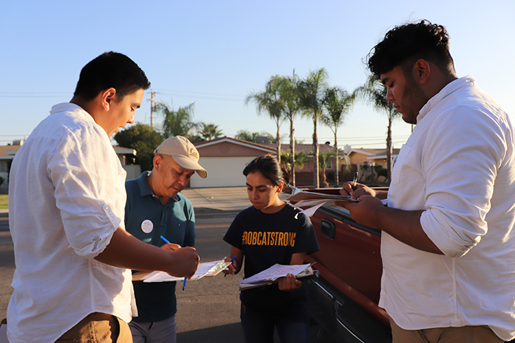 Bryan Osorio Trujillo canvasses in Delano, California, with three young colleagues, in his run for a city council position. They are huddling over plan.