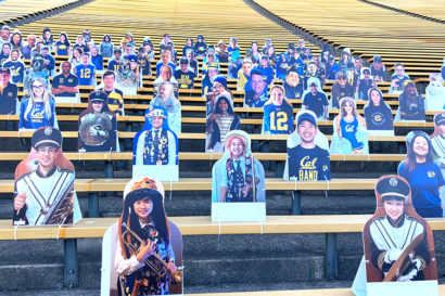 cardboard cutouts of each band member in the stands at a football game