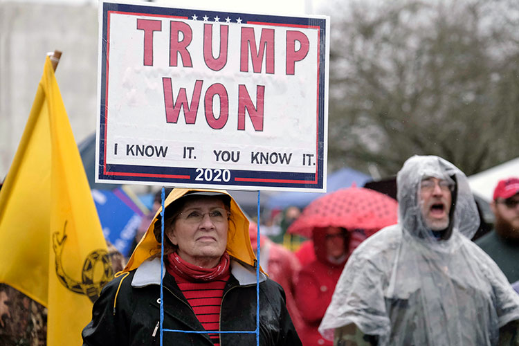 Woman holds protest sign proclaiming Donald Trump's 2020 victory, months after he lost the election. The signs reads "Trump Won. I know It. You know it."