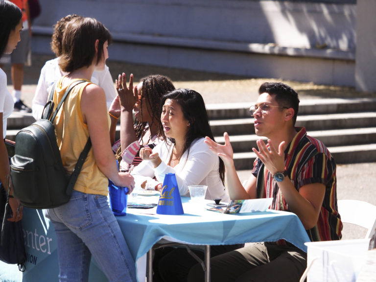 students talk to each other outside at tables
