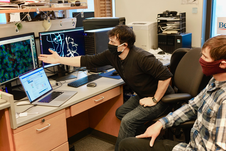 two researchers looking at protein structure on a computer screen