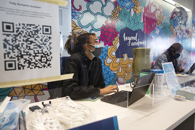 Undergraduate Abena Bakevna hands out free Cal masks to students who come to an ASUC booth set up in the Martin Luther King Jr. Student Union. She sits behind a plexiglass window during the pandemic.
