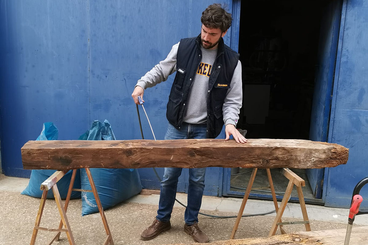 a man with a tool working on a big piece of wood