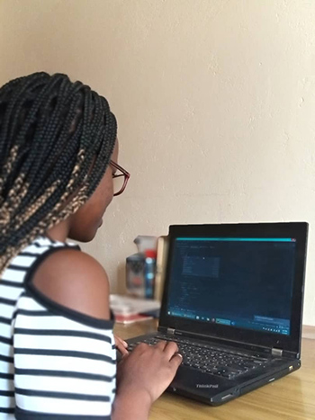 Martha Toni Atwiine works on her laptop in Uganda, taking part in the Afro Fem Coders group to learn coding.