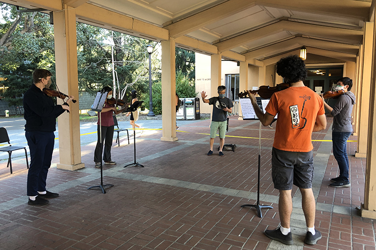 In the breezeway between Morrison and Hertz halls, four violinists from the UC Berkeley Student Orchestra practice with their instructor.