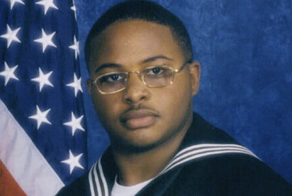 Tyrone Wise in a military uniform with the American flag behind him