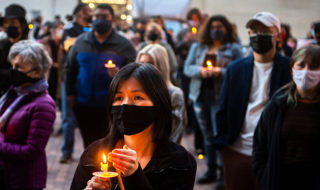 A photo of a crowd of people holding candles at twilight