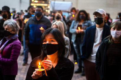 A photo of a crowd of people holding candles at twilight