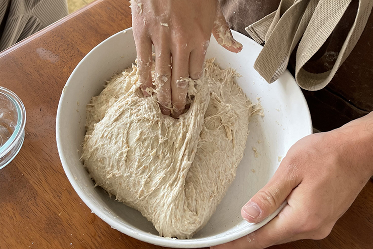Carolyn Hong works with a bowl of sourdough bread dough.