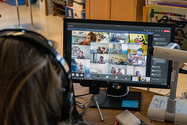 teacher wearing headphones conducts a class via Zoom video call