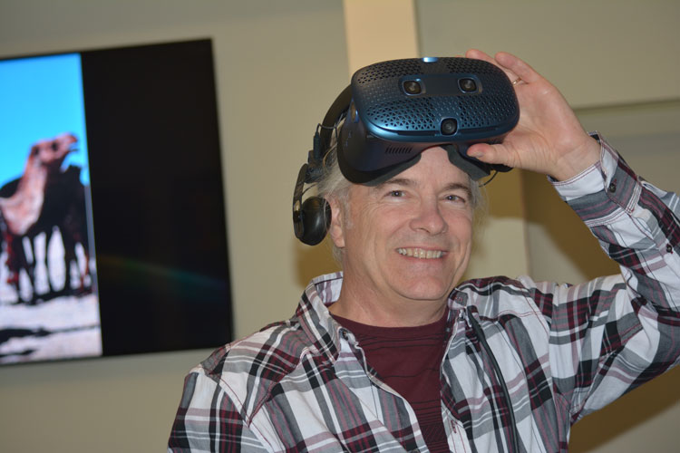 Chris Hoffman, research data manager at UC Berkeley lifts A VR headset
