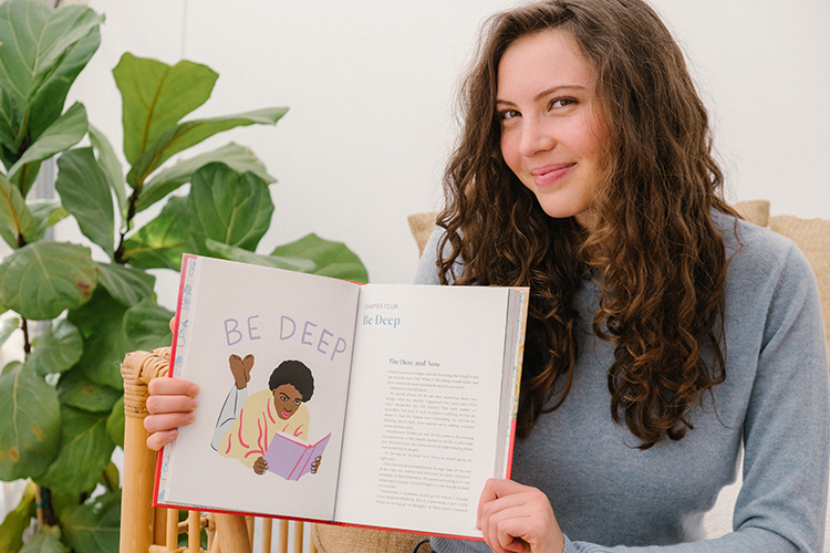 Sadie Radinsky, a first-year student and teen author, holds open a page of her new book of advice for girls and young women about being themselves and loving themselves.