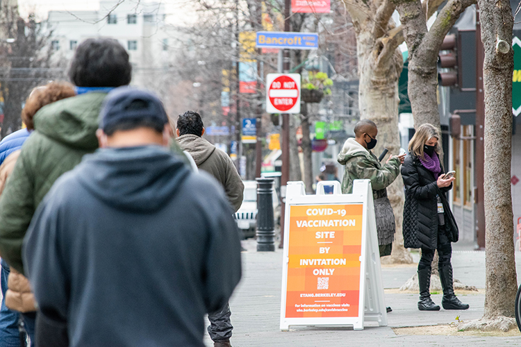 A line of people with COVID-19 vaccine appointments forms outside the student union.