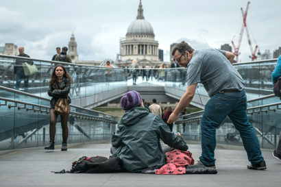 man giving something to a person sitting on the ground