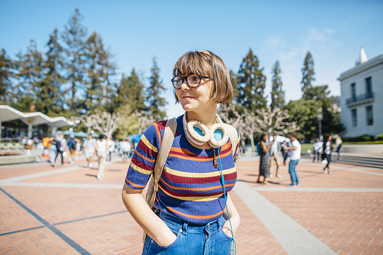 student on campus wearing striped shirt and smiling