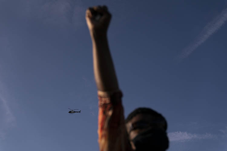 a woman holds her fist in the air while a helicopter hovers behind her