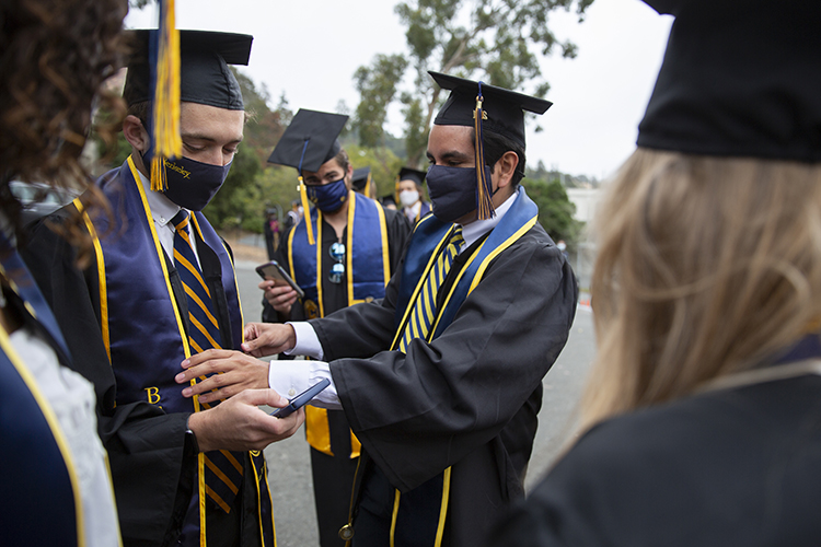 Graduate Eric Manzo helped straighten friend K.C. Hunt's stole before they cross the Greek Theatre stage.