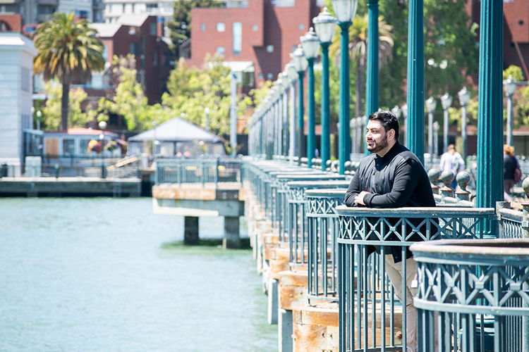 Leaning on a railing, Harris Mojadedi look out at San Francisco Bay from Pier 7)