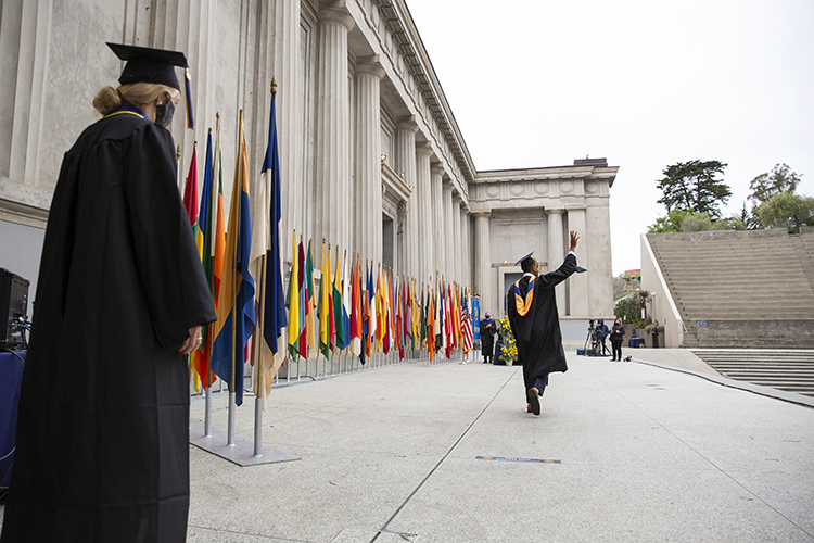 Navneedh Maudgalya, who is graduating with a master's degree in electrical engineering and computer sciences, waves to the camera, and to his family and friends watching remotely, as he begins his walk across the Greek Theatrestage.