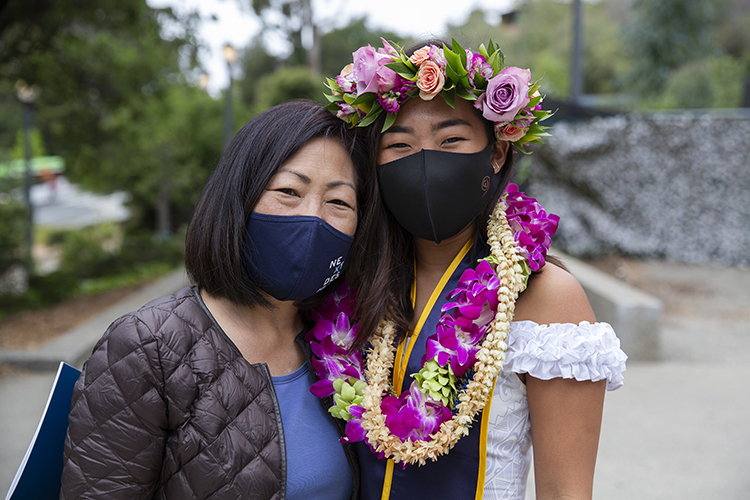 Masked family members Paris Sato and her mother, Karen Sakamoto, from Hawaii, pose for a graduation photo just outside the Greek Theatre gates.