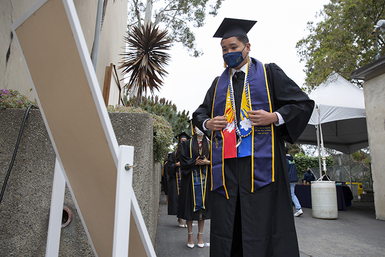 Graduate Telian Espanta checks his reflection in a mirror as he readies to cross the Greek Theatre stage.