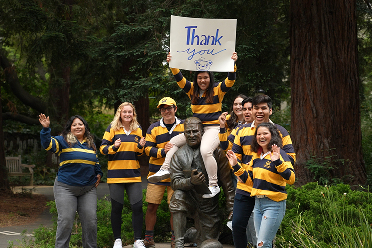 a group of students in blue and gold hold a sign saying thank you