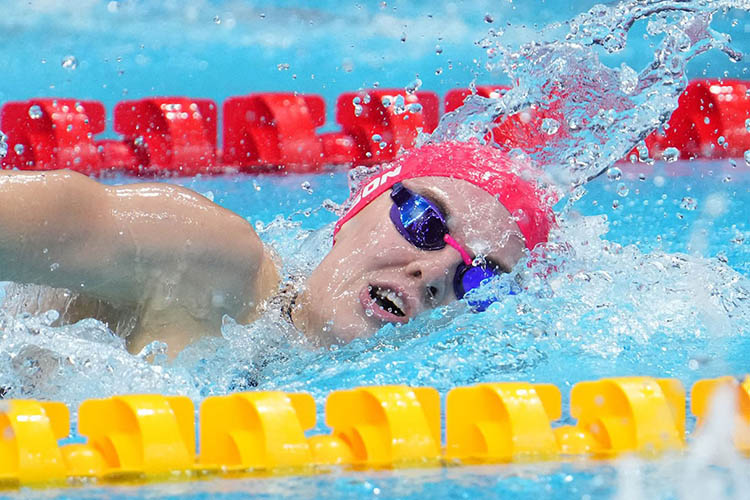 a woman in a cap and goggles swims in a pool