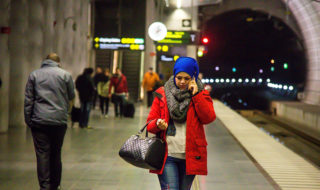 woman walking and talking on a phone at a subway station at night