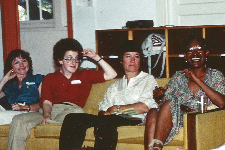 four people sit on a couch smiling in the 1980s