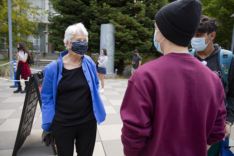 carol christ in a mask talks to a student at the start of fall semester 2021