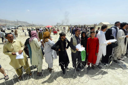 people lined up in the desert in front of barbed wire