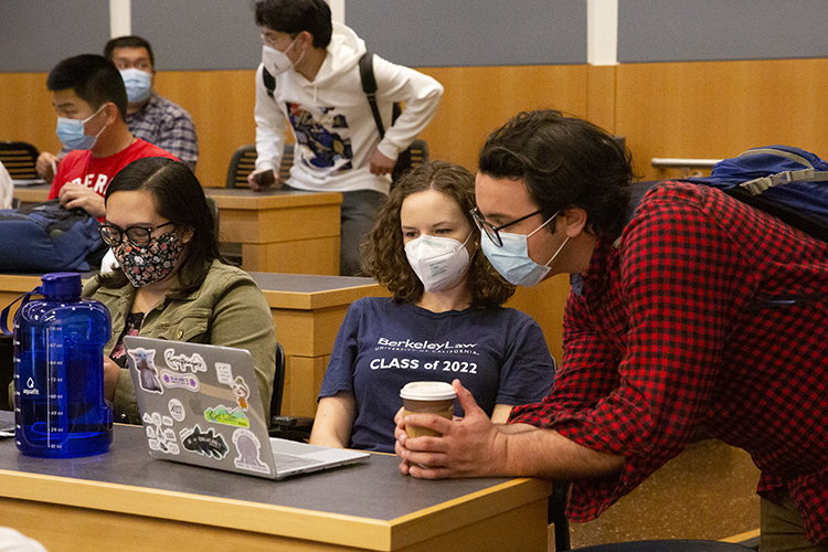 Berkeley Law students in masks talk before class begins.