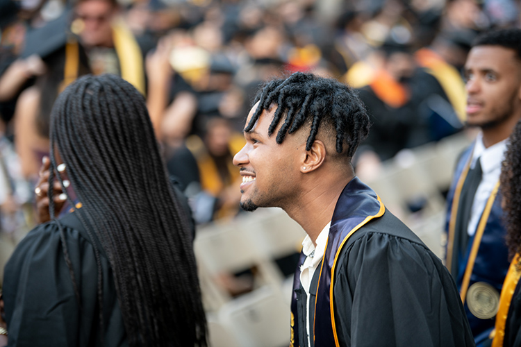 An African American grad in the Class of 2020 smiles while looking out at the events at the Greek Theater ceremony.