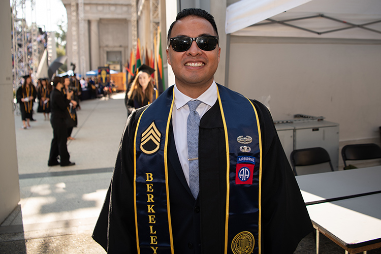 Ο απόφοιτος του UC Berkeley και ο βετεράνος του αμερικανικού στρατού, Rodrigo Ramirez, χαμογελά πίσω από τα γυαλιά ηλίου του και φορά τη στολή του στην προσωπική τελετή αποφοίτησης του 2020 στο ελληνικό θέατρο.