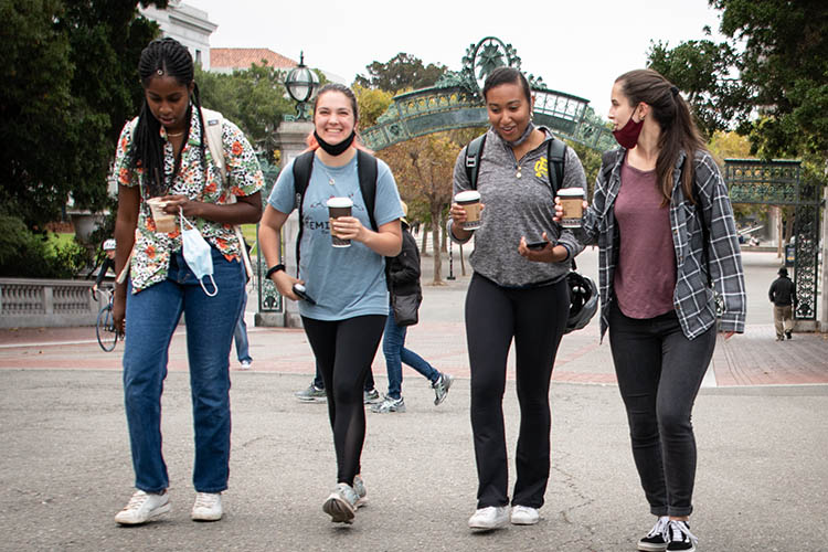 four students walk with coffee on sproul plaza