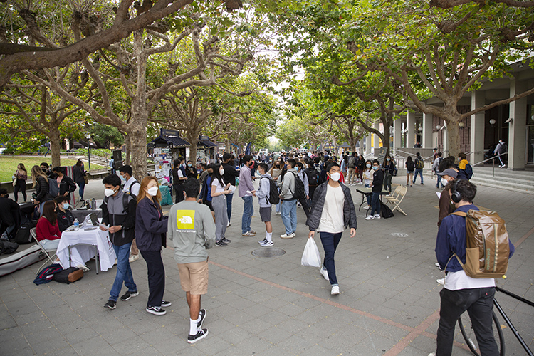 Students in masks walk through Sproul Plaza where tabling is back after a break during the pandemic.