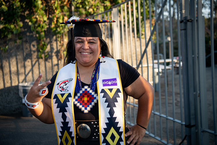 Class of 2020 grad Smoke K. Johnson, who is Native American, smiles with her colorful stole, decorated with Native American designs