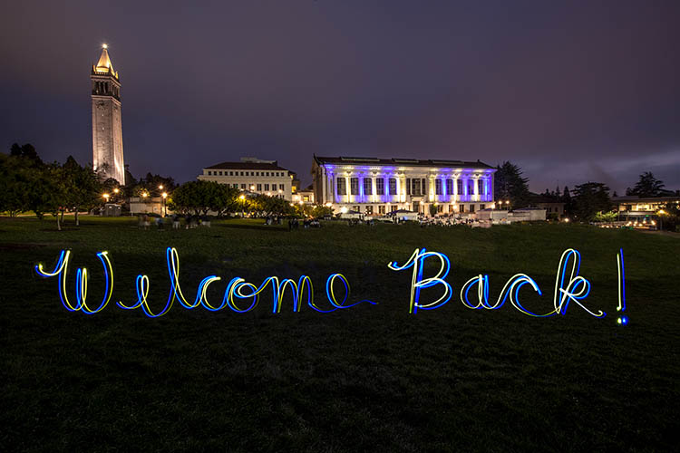 the words "Welcome back" written in light in front of doe library and sather tower