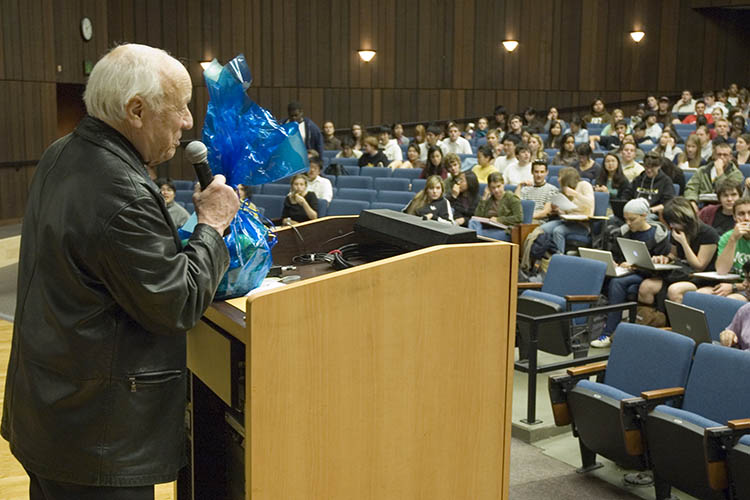 litwack speaks to a crowd of people in Wheeler auditorium