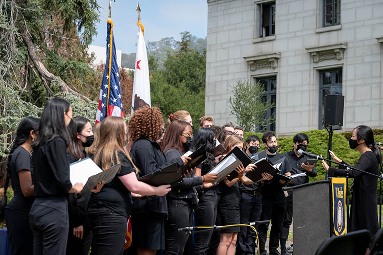students in black sing in a chorus during the ceremony