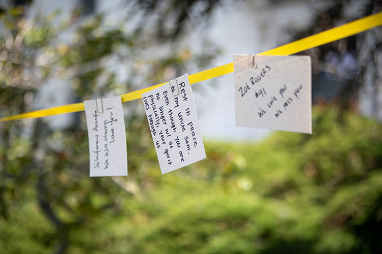 cards written by mourners hang on a yellow ribbon. The center card reads 