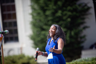 a woman in a blue dress sings a song during the service