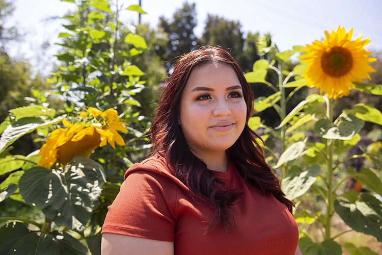 portrait of elizabeth cardenas smiling with sunflowers behind her