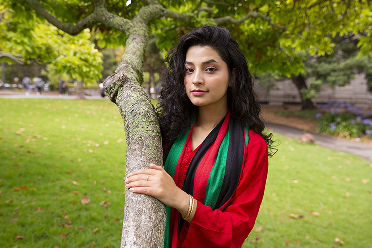 Maryam Karimi stands with her hand on a tree