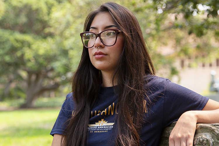 Sariel Sandoval, a new student at Berkeley, looks into the distance through her large eyeglasses and wearing a UC Berkeley T-shirt.